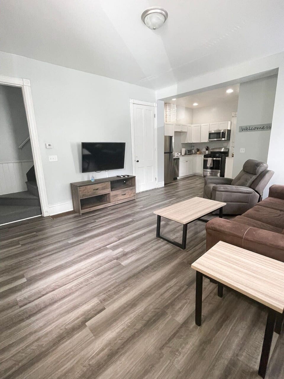 Spacious living area flowing into a sleek kitchen, featuring large windows, and a comfortable couch.