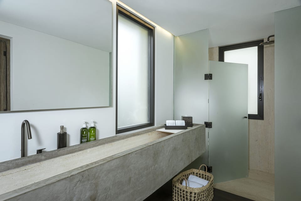En-suite bathroom with a concrete trough vanity and walk-in shower at Villa Marena in Hacienda Beach, Cabo San Lucas.