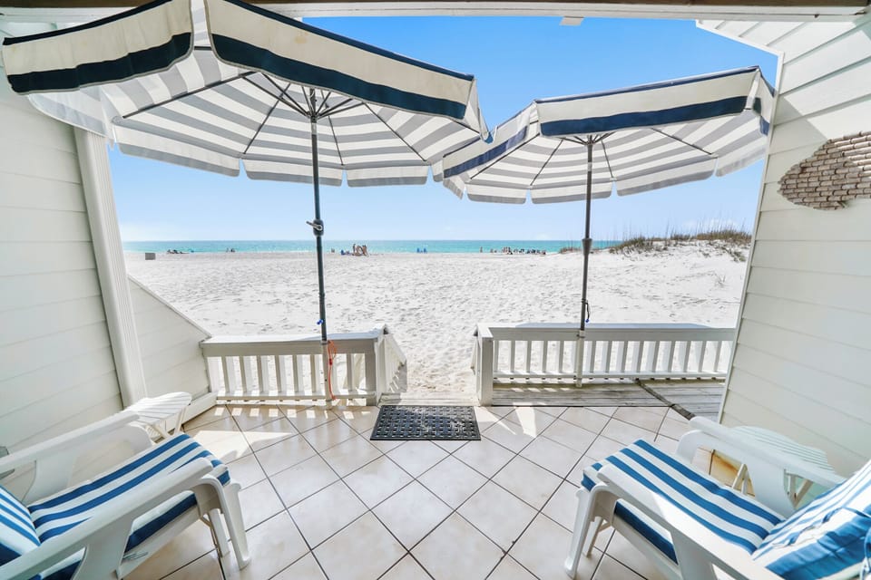 Step onto your private beachfront terrace where striped umbrellas shade comfortable lounge chairs. Crystal-clear waters and white sand await just steps away.