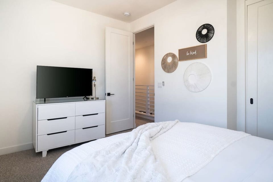 Bedroom w/ TV, dresser & open doorway leading to adjoining space