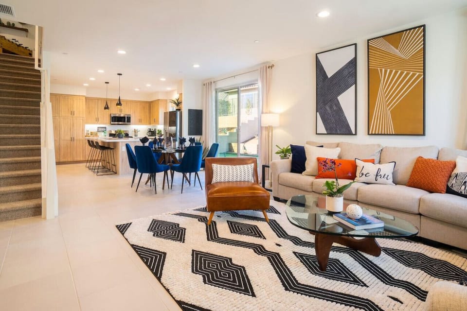 Modern living area w/ cozy sofa, bold accents & open flow into the dining space