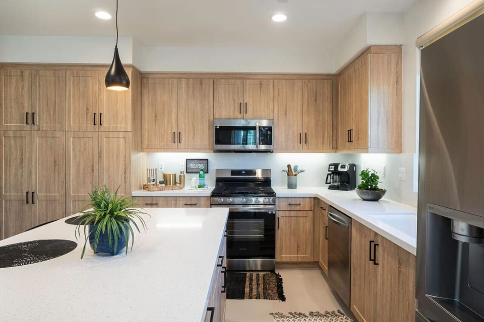 Sleek kitchen w/ wood cabinetry, island seating & stainless appliances