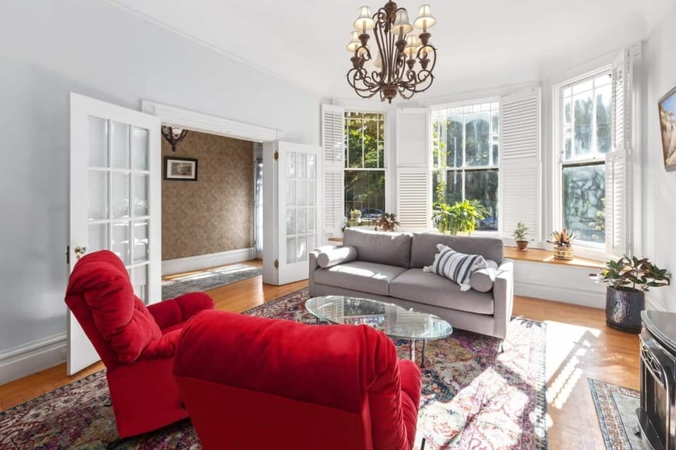 Sun filled living room with comfortable couch and swivel rocking chairs. View to Buena Vista Park across the street.
