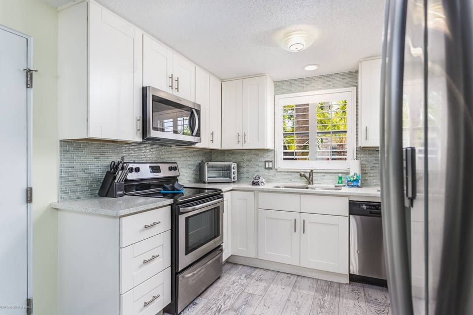 Modern white and stainless kitchen stocked with dishes, pots and pans