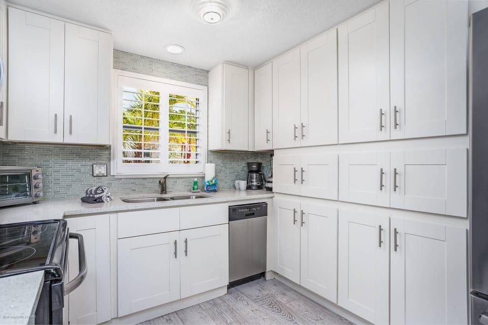 Modern kitchen with stainless appliances and solid stone counters stocked with cookware (no food items)