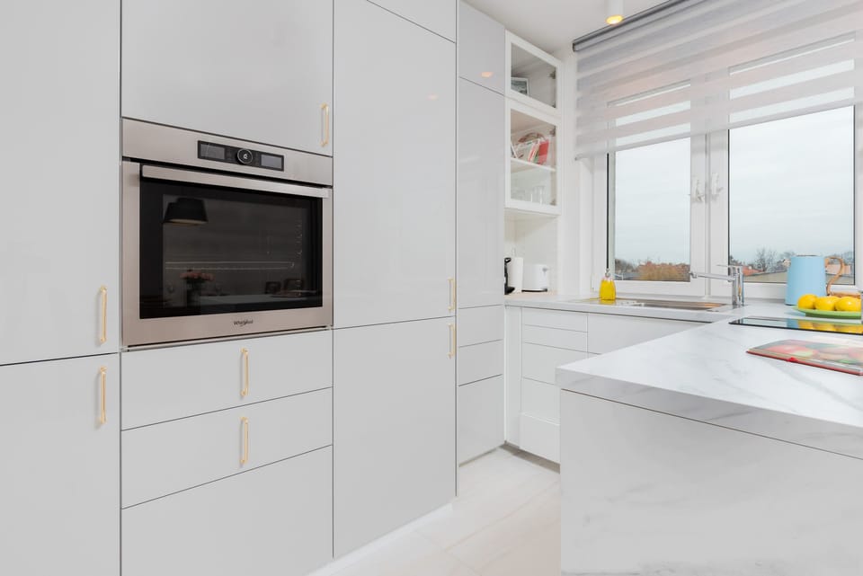 A sleek kitchen with a built-in oven, white cabinets, and bright, functional space.
