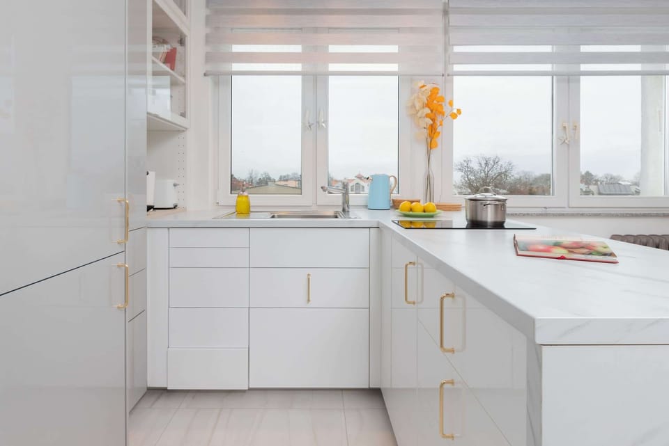A minimalist kitchen with white cabinetry, built-in appliances, and ample natural light.
