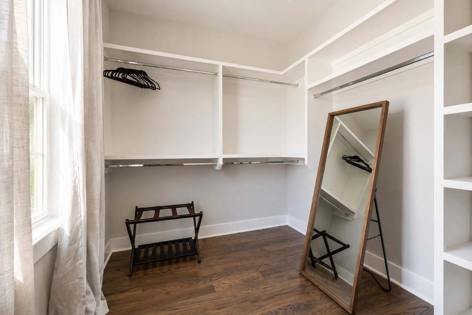 Large walk-in closet with built-in shelving, ample hanging space, and a full-length mirror for added convenience during your stay.