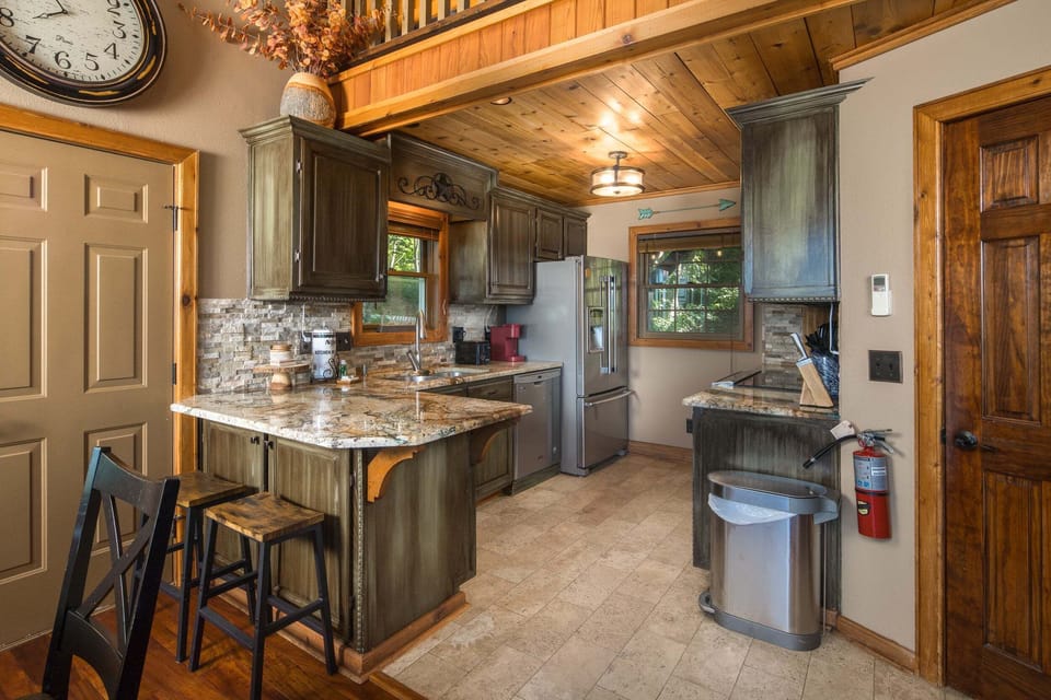 Fully equipped kitchen with granite countertops, stainless steel appliances, and bar seating