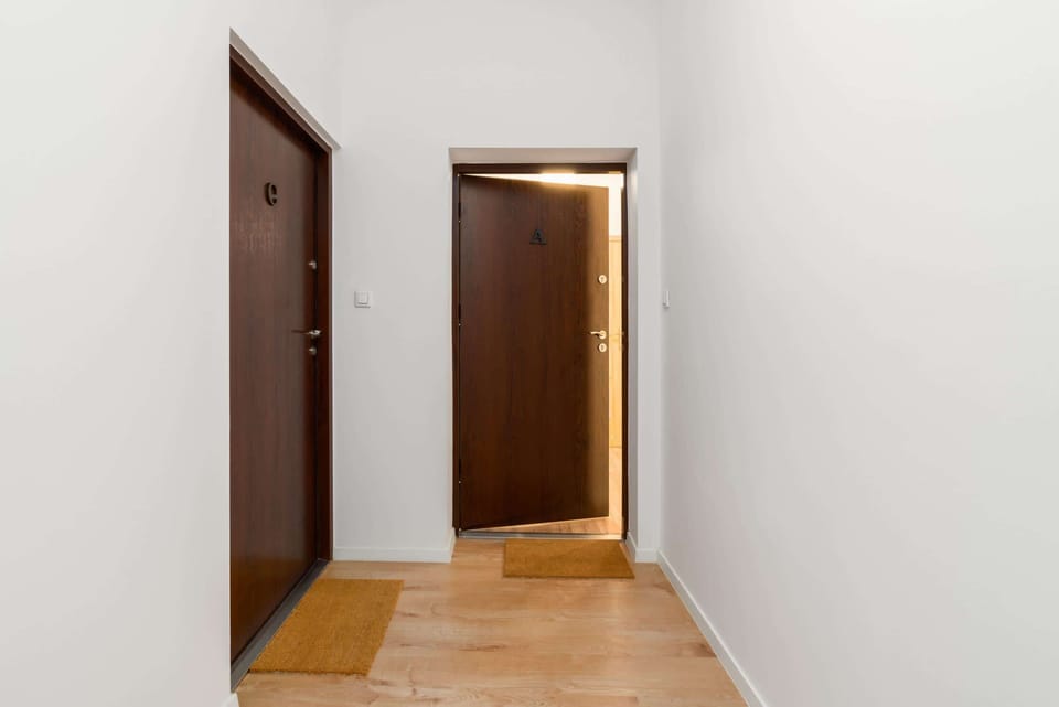 An interior hallway with a wooden door, leading to the apartment entrance.
