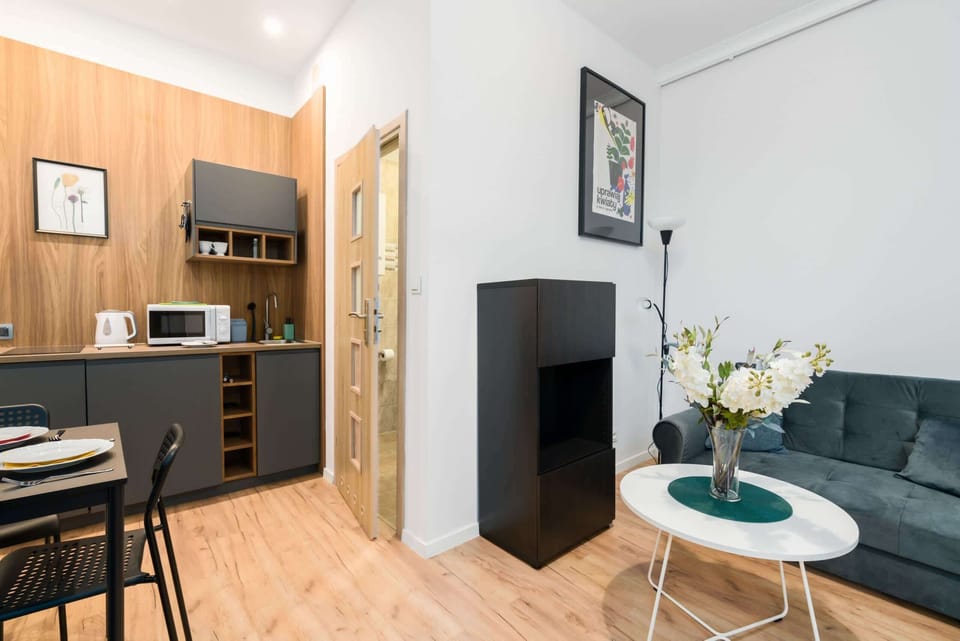 A kitchenette with wooden cabinets, a microwave, and a dining table nearby.
