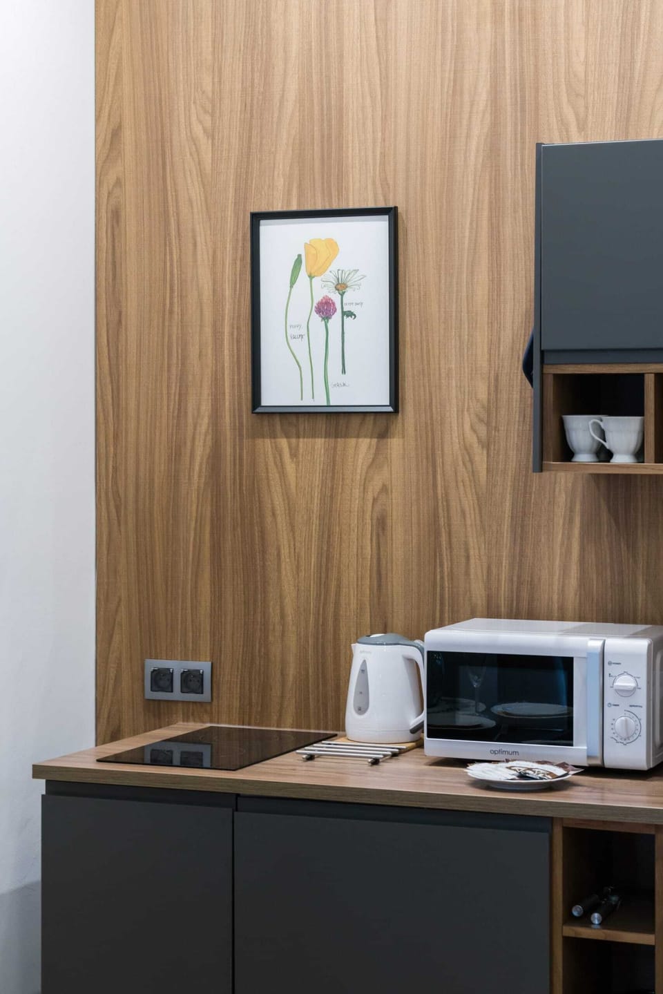 A kitchenette with wooden cabinets, a microwave, and a dining table nearby.

