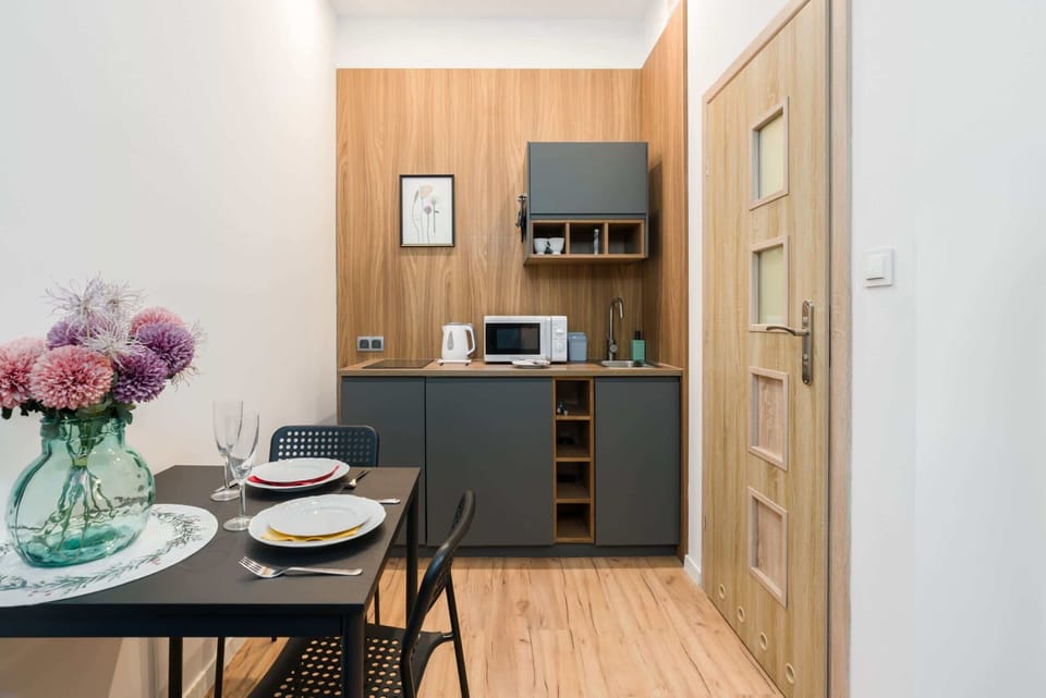 A compact kitchenette with wooden cabinetry, modern appliances, and a small dining table.
