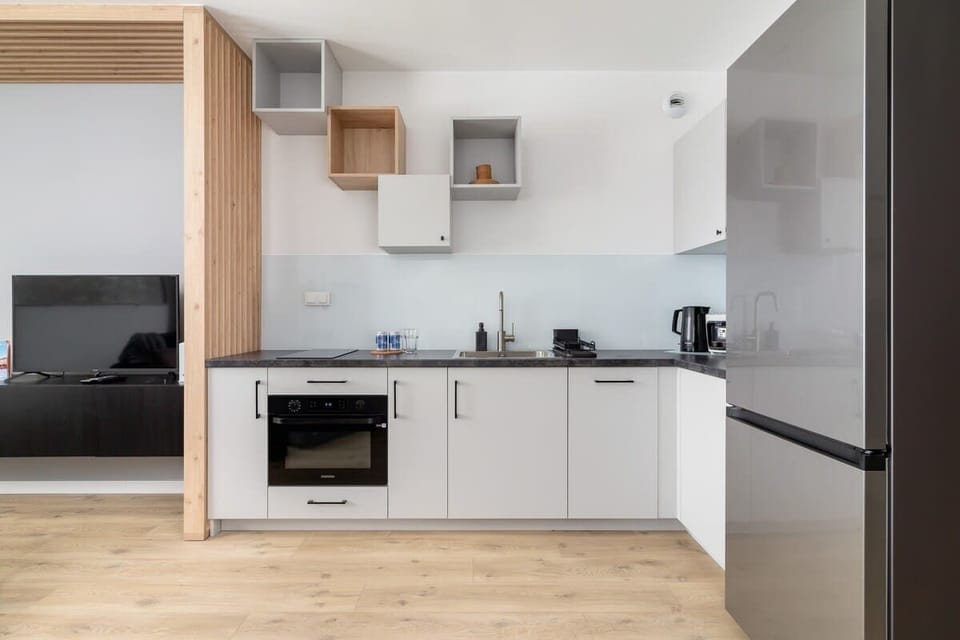 A minimalist kitchen with white cabinets and wooden accents.
