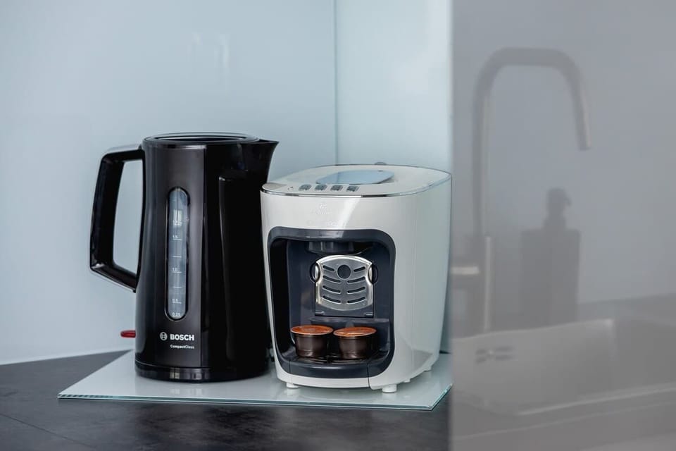 A coffee station with a kettle and coffee maker.
