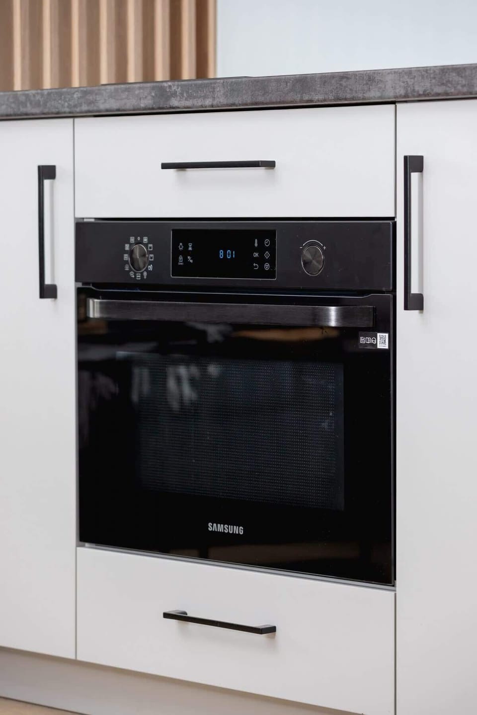 A close-up of a modern oven integrated into white cabinetry.

