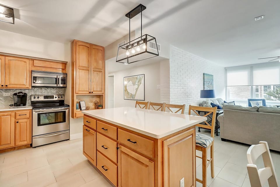 Your modern kitchen features warm wood cabinets, granite counters, and stainless appliances, seamlessly flowing into the bright living space.