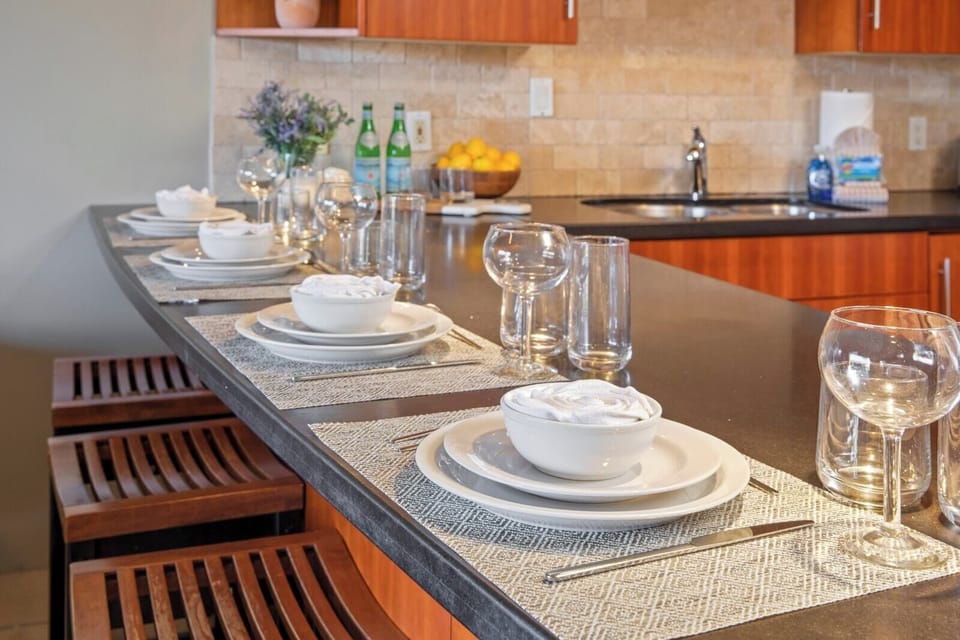 Gather around a spacious island with bar seating, stone countertops, elegant place settings, and warm wood finishes    
