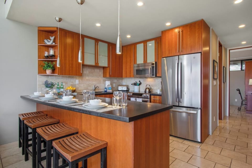  This designer kitchen offers polished countertops, a breakfast bar, and custom cabinets in a rich cherry wood tone   