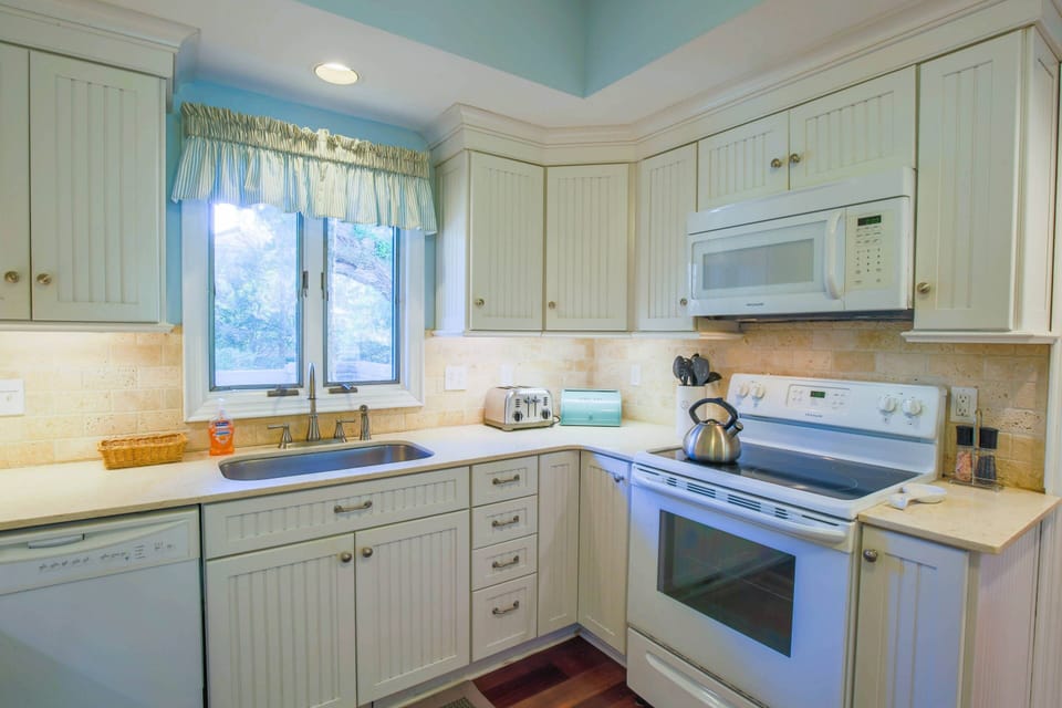 The kitchen features white appliances and white cabinets.