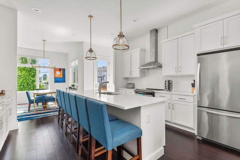 - Bright kitchen with long island seating perfect for group stays   - White cabinets and stainless appliances create a clean modern look   - Open layout connects kitchen and dining for easy vacation hosting
