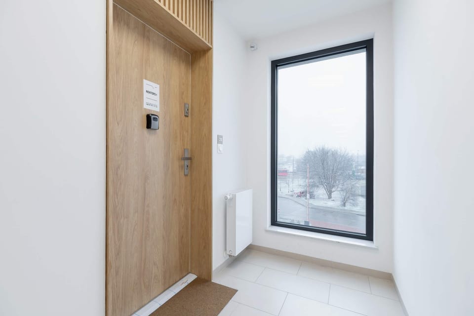A bright stairwell with natural light coming through a large window, featuring minimalist design.

