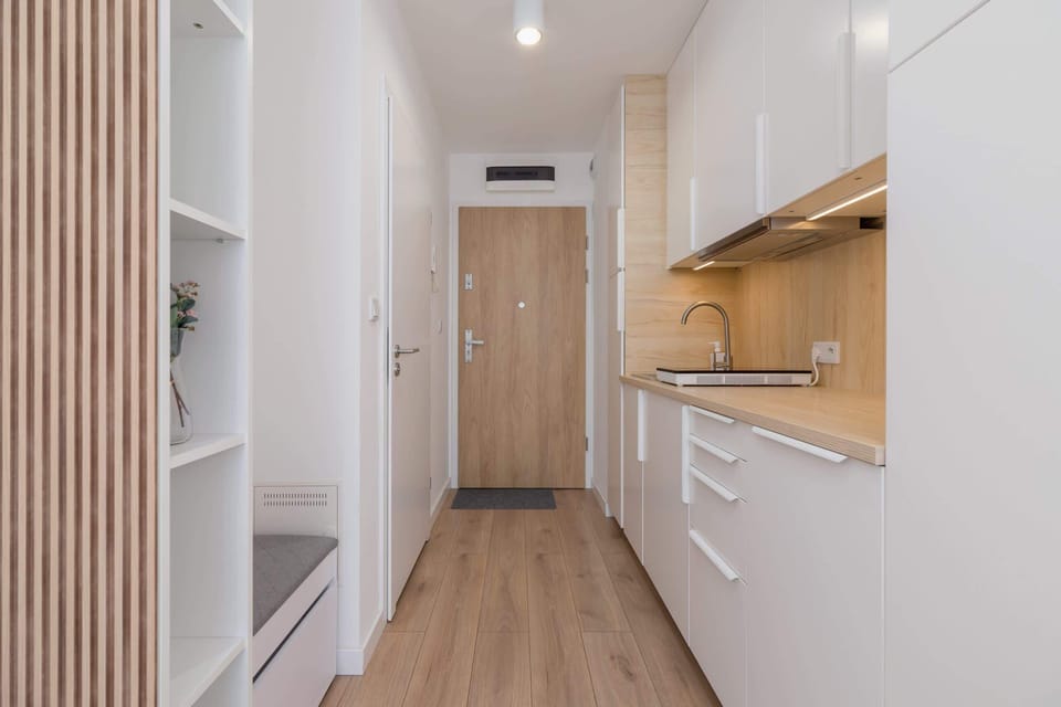 A bright hallway leading to the kitchenette and living area, with wooden finishes.
