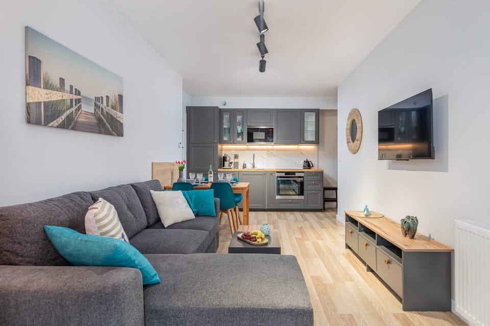A living room with a gray sofa, coffee table, and a kitchenette in an open-plan layout.
