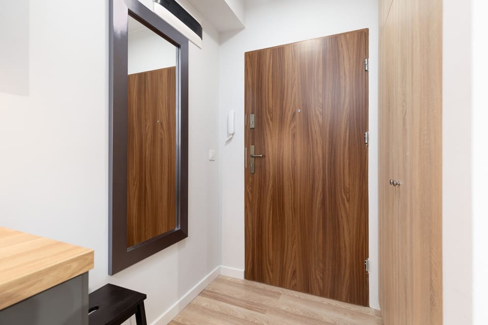 An entryway with a large mirror, wooden door, and modern lighting.
