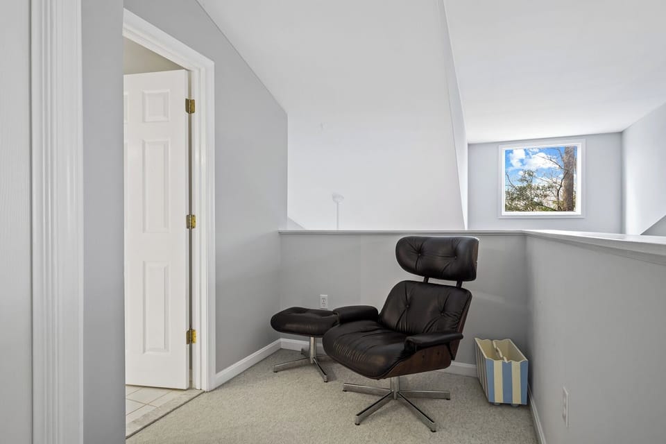 54021 Sand Dollar Court -desk area - Functional loft landing area featuring a modern black leather lounge chair with an ottoman, perfect for a quiet reading nook.