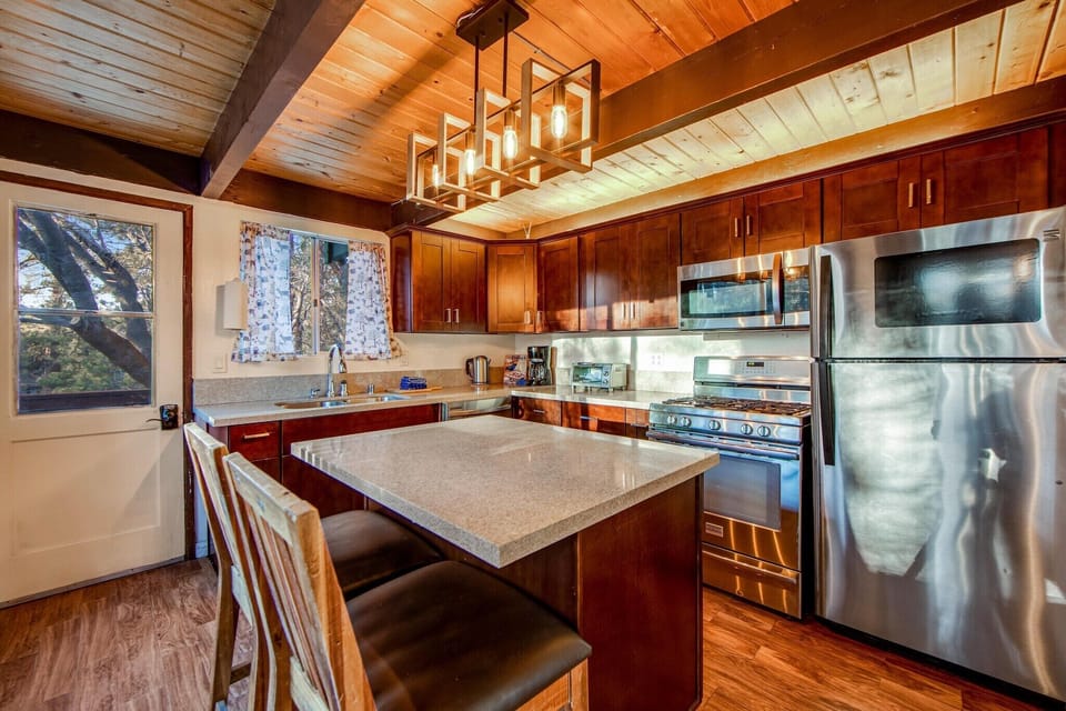The full kitchen features stainless steel appliances and a breakfast bar