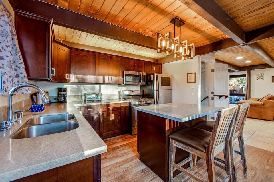 The full kitchen features stainless steel appliances and a breakfast bar