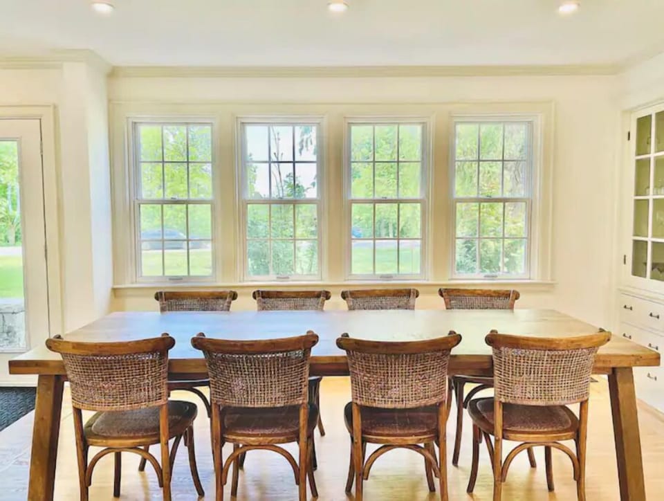 Spacious dining room with river views and seating for 8 at a rustic table.