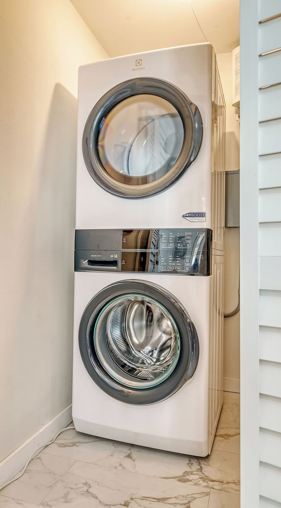 In-unit laundry area with stacked front-load washer and dryer