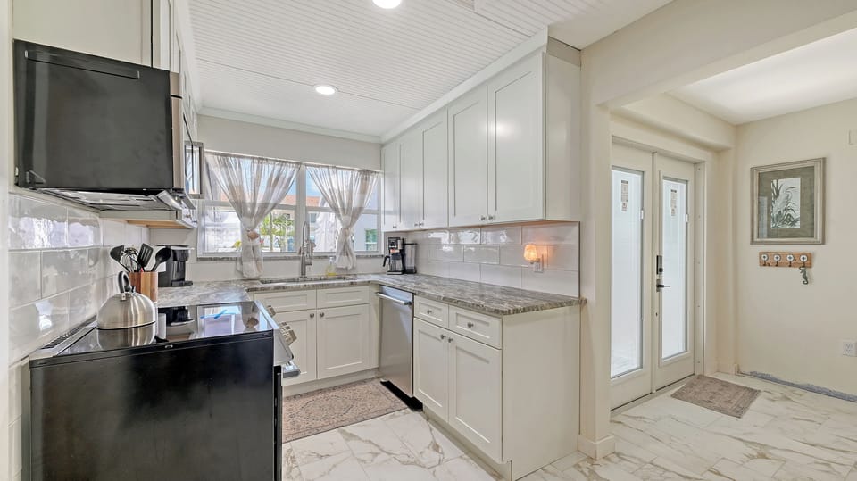 Kitchen with dark cabinetry, professional range hood, and glass doors to the exterior