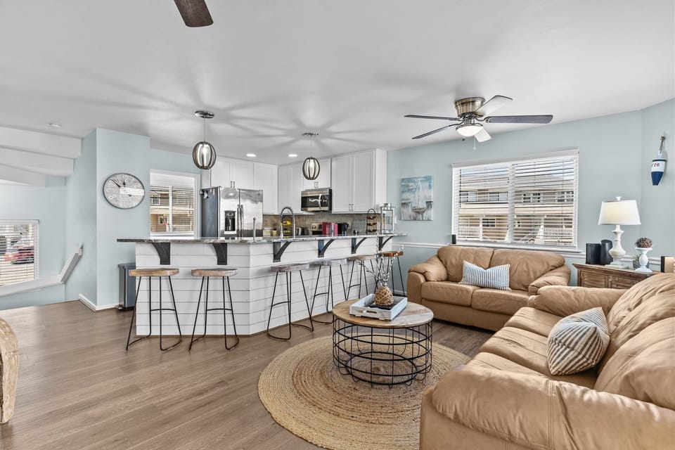 Relax in your open-concept living space where coastal blues meet warm leather seating, perfect for gathering around the stylish coffee table.