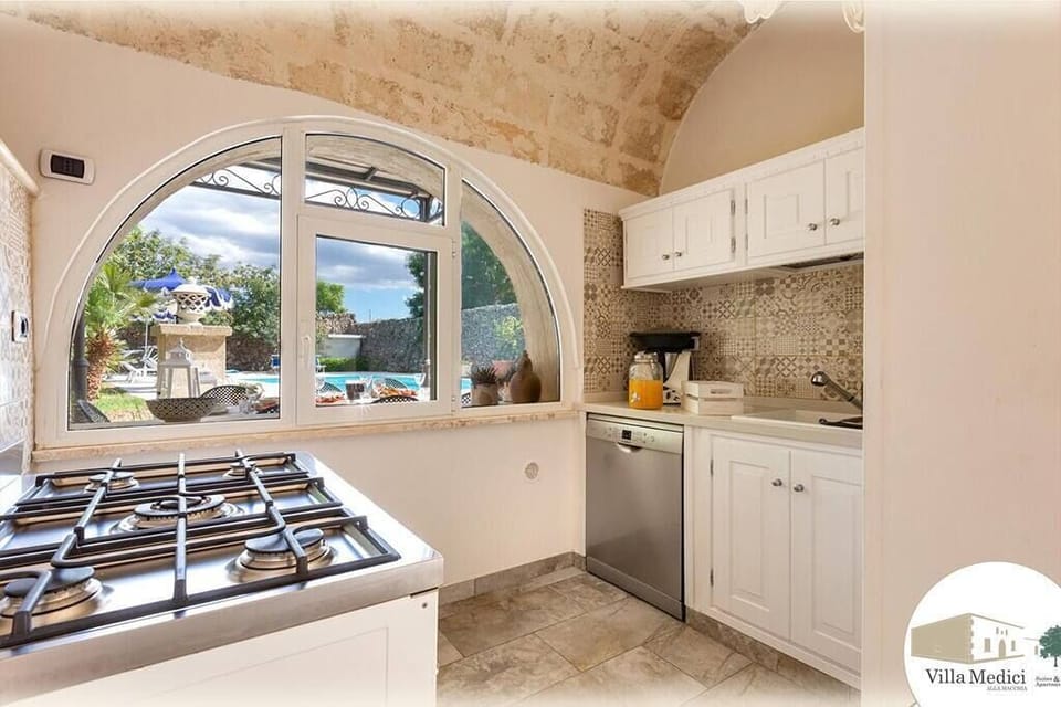 Cucina della Depandace con una caratteristica finestra mezza luna affacciata sulla piscina