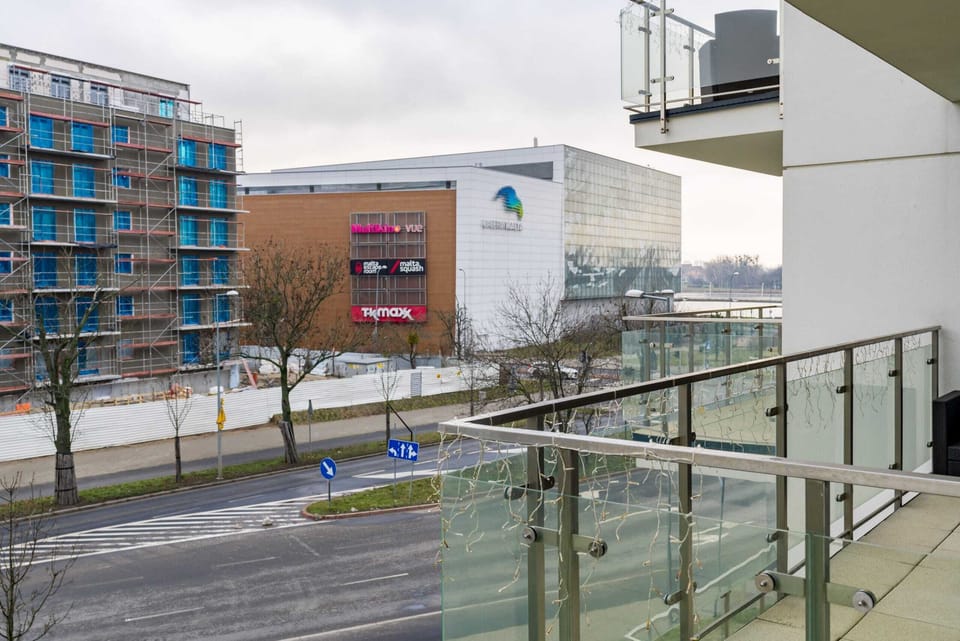 A view from the balcony showcasing nearby modern buildings and a busy street.
