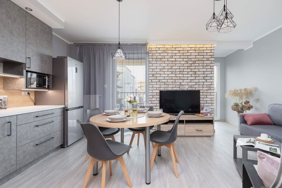 A living and dining space with a stylish kitchen, a dining table, and a decorative brick wall.
