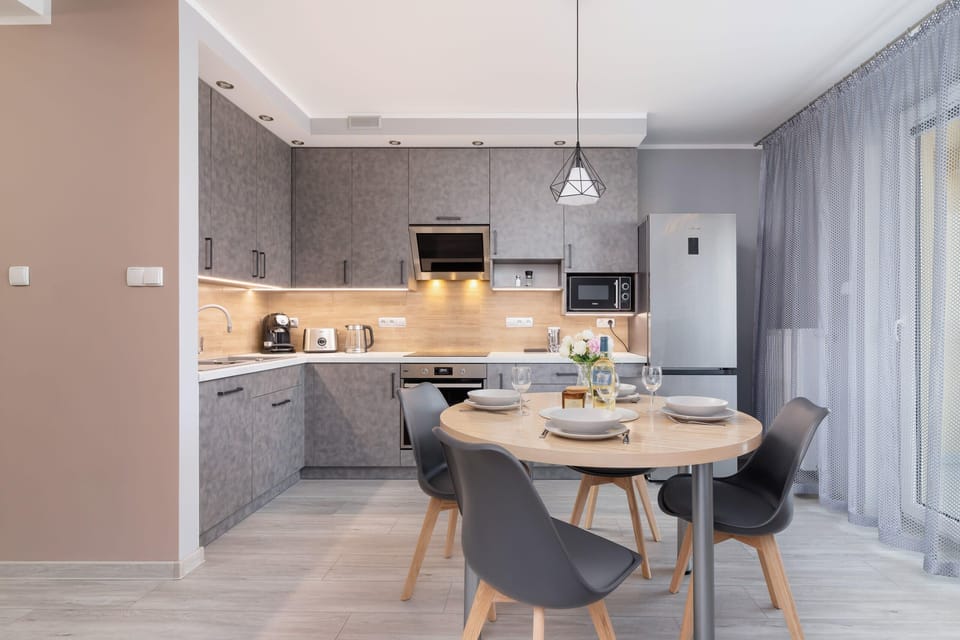 A kitchen and dining area with modern furniture and soft, neutral tones.

