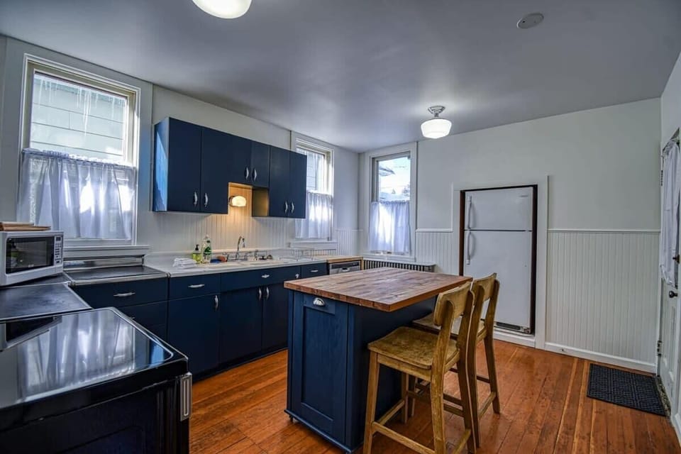【Kitchen — Full View】 Full-size fridge, range, dishwasher, butcher island — groceries for 10 without playing Tetris.