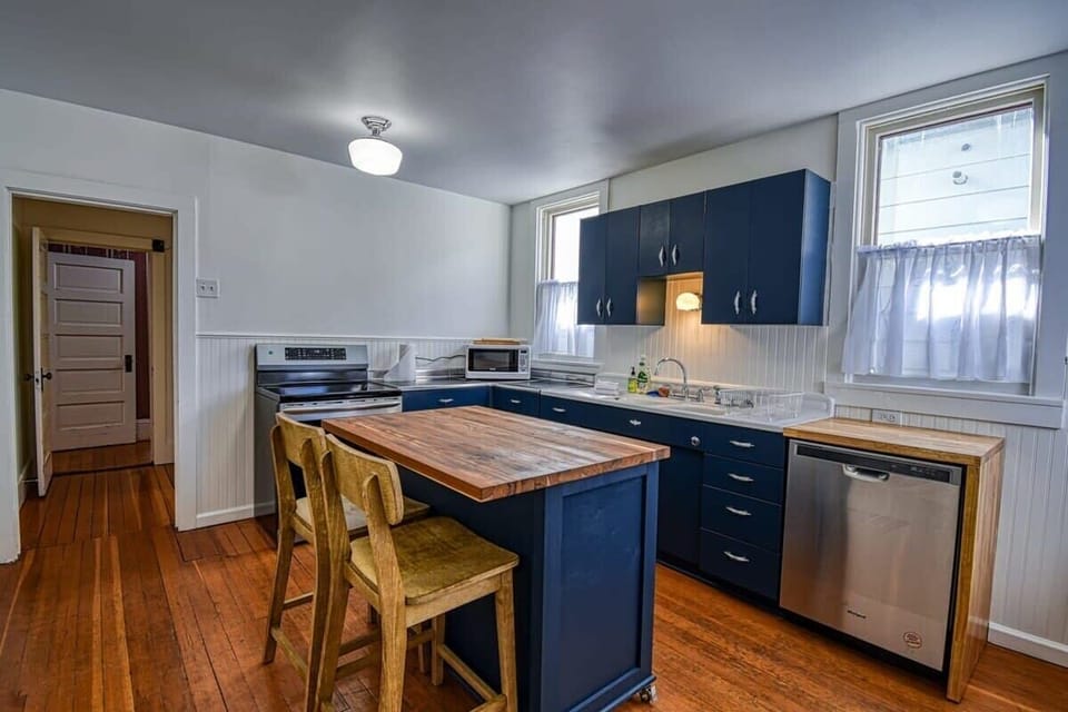 【Kitchen】 Navy cabinets, butcher-block island, induction range, dishwasher — cook a full group dinner without crowding.