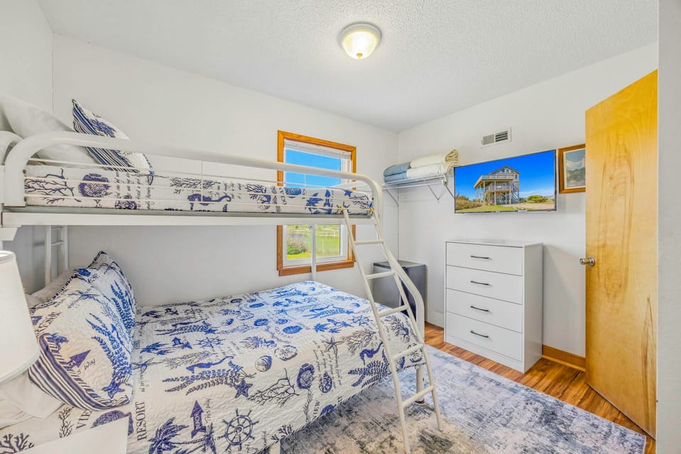 Cozy bunk room with nautical-themed bedding, perfect for kids or groups. You'll love the coastal charm and practical storage.