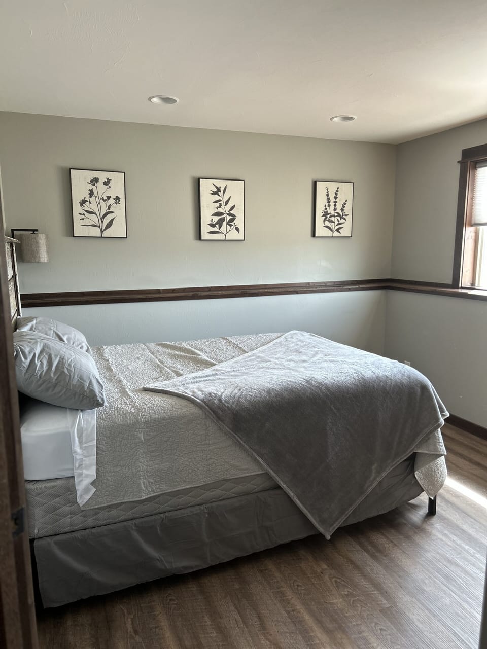 Basement bedroom with queen bed and lamp.