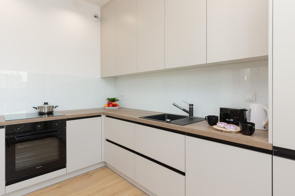 A sleek kitchen with white cabinets, a black countertop, and clean lines.
