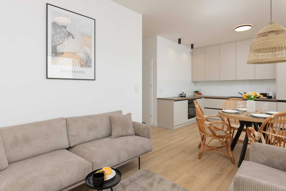 A spacious living and dining area with a gray sofa, a wooden table, and modern decor.
