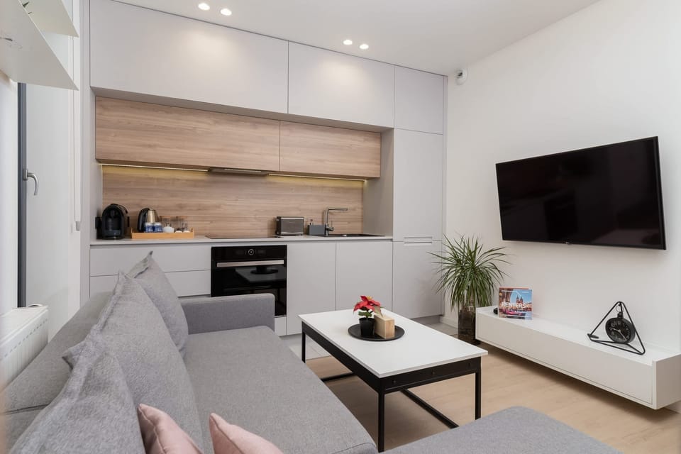 A living area with a sectional sofa, coffee table, and a mounted TV, designed in neutral tones.
