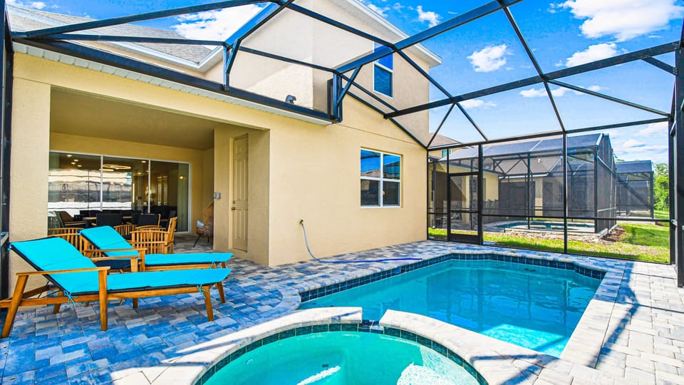 Screened pool and spa with lounge chairs, patio seating, and sunny views.