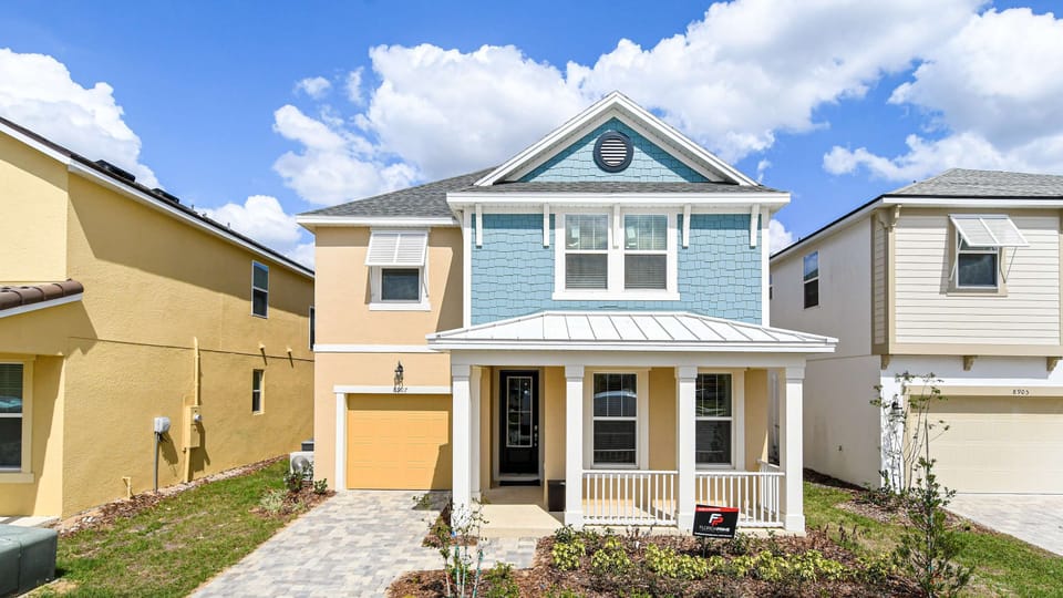 Charming two-story home with a porch, modern facade, and paved driveway.
