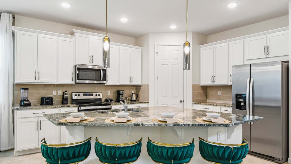Elegant kitchen with marble island, velvet bar stools, and modern stainless steel appliances.